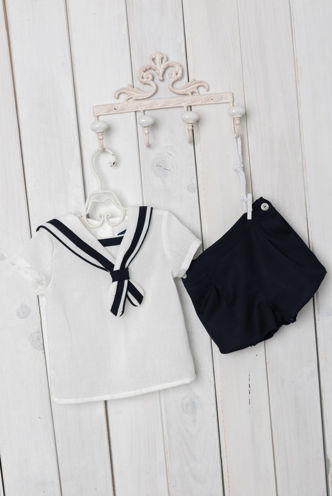 Children's sailor outfit with a white top and navy shorts on a wooden surface