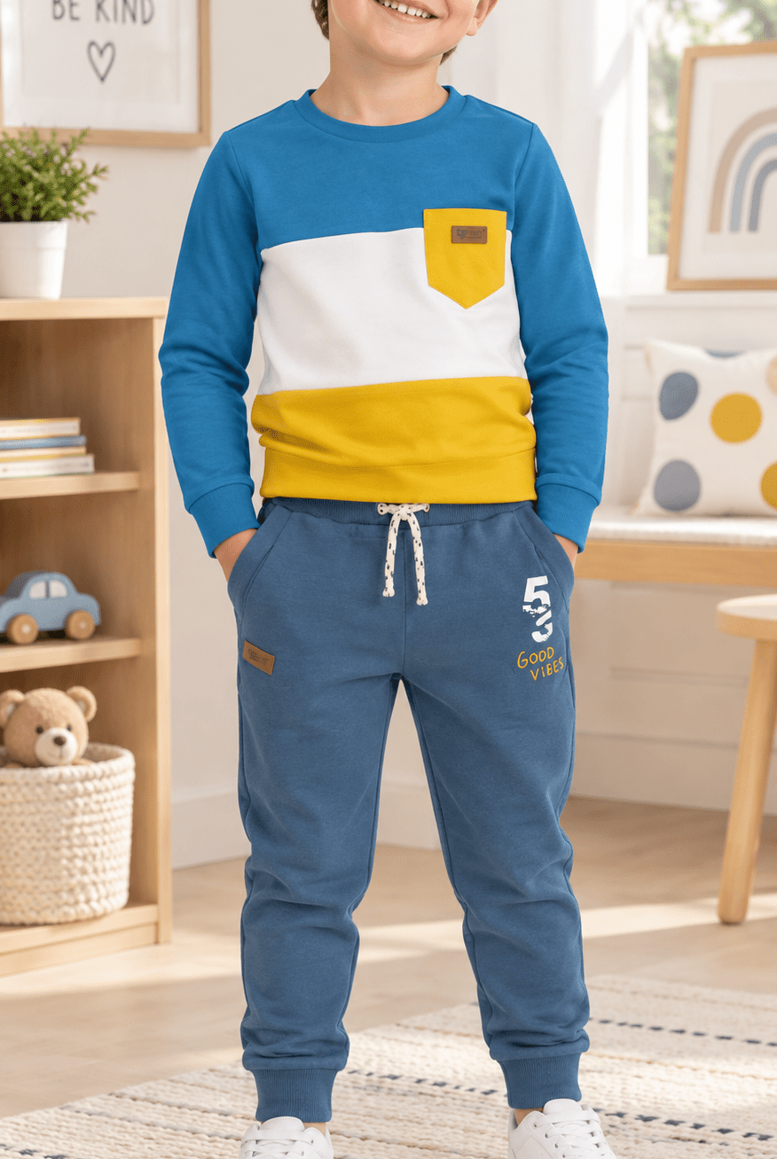 Young boy wearing blue tracksuit bottoms and matching long sleeved t-shirt