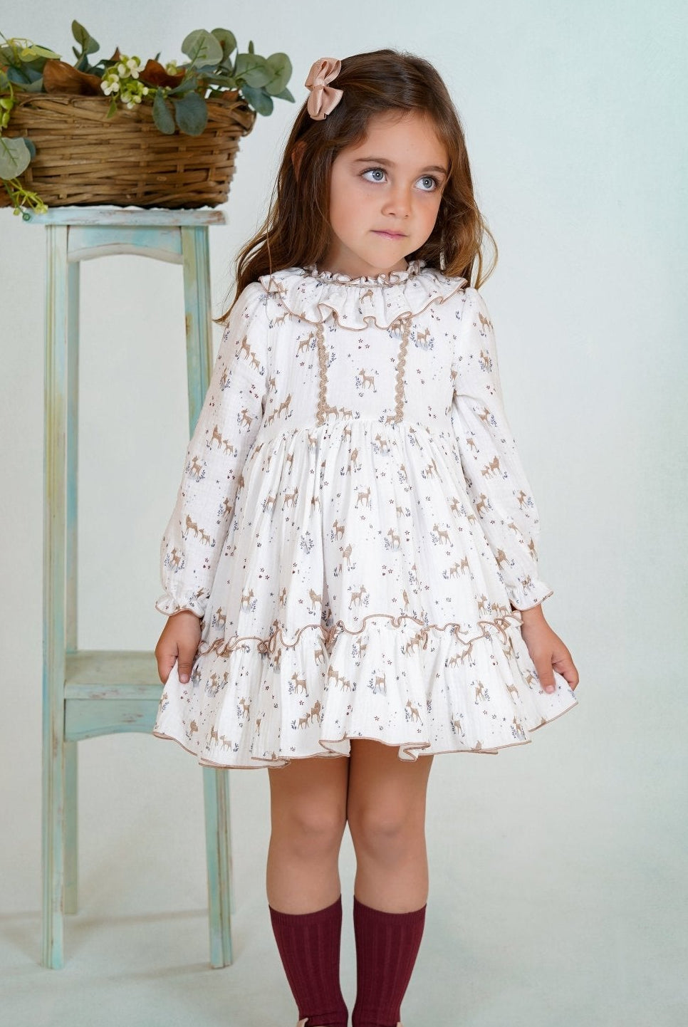 Girl wearing a long-sleeved deer print dress with ruffled collar and hem from DBB Collection AW25.