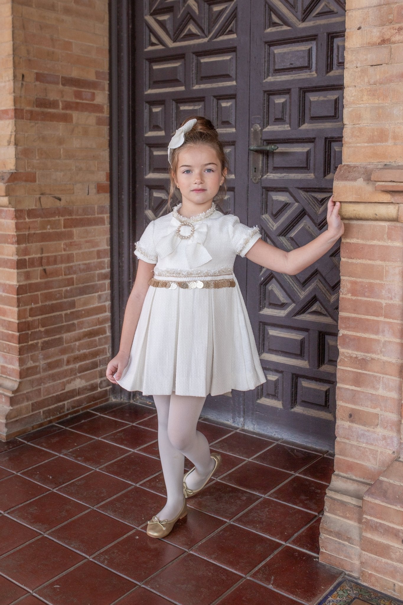 Girls boutique cream dress with bow detail and gold trim, styled with hairbow