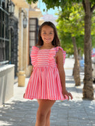 La Peppa SS26 Girls Neon Pink Stripe Summer Dress Modelled in a street setting.
