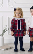 Miranda AW26 young child wearing the baby girls tartan print in red and navy dress with matching knickers. 