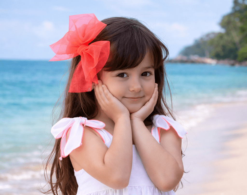 Child wearing Babine SS26 White and Neon Orange Trim Dress and matching hairbow. 