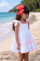 Child wearing Babine SS26 White and Neon Orange Trim Dress and matching hairbow. 