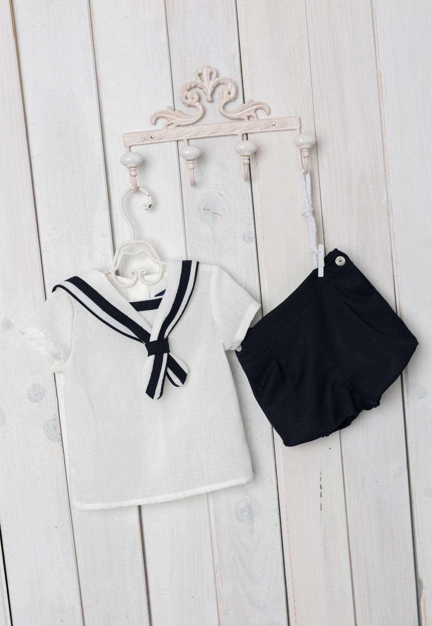 Children's sailor outfit with a white top and navy shorts on a wooden surface