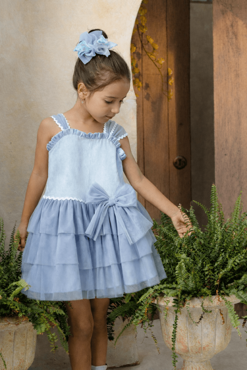 Girl wearing Basmarti SS26 Camelia blue Spanish occasion dress outdoors