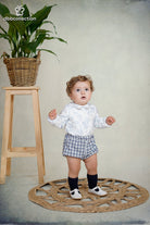 Baby boy wearing a blue woodland print shirt with Peter Pan collar and navy gingham shorts from DBB Collection AW25.