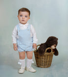 Baby boy wearing blue gingham short dungarees with white Peter Pan collar shirt from DBB Collection AW25.