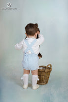 Baby boy wearing blue gingham short dungarees with white Peter Pan collar shirt from DBB Collection AW25.