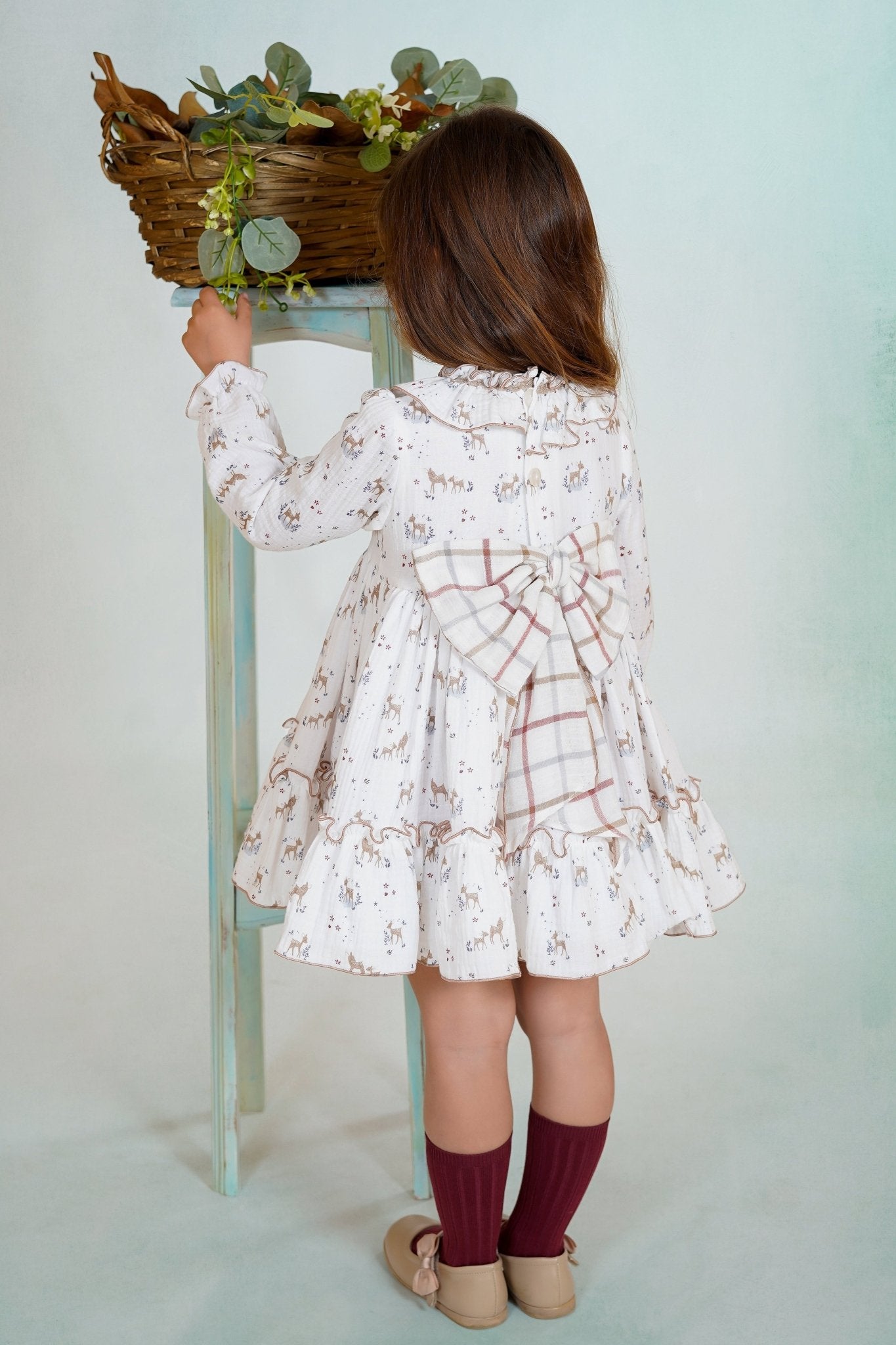 Girl wearing a long-sleeved deer print dress with ruffled collar and hem from DBB Collection AW25.