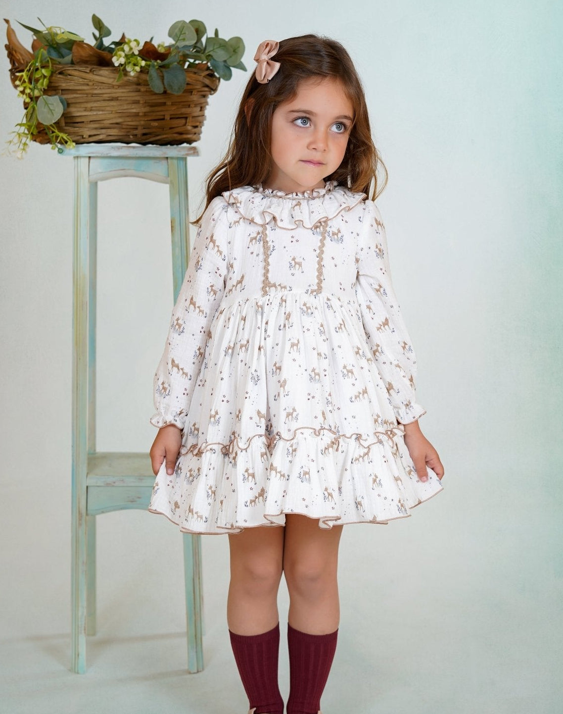 Girl wearing a long-sleeved deer print dress with ruffled collar and hem from DBB Collection AW25.