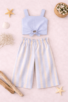 Light blue top and striped shorts set on a pink background with decorative elements.