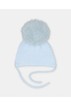 A light blue knit baby beanie hat with a fluffy pom-pom on top and braided ear ties, shown against a plain light gray background.