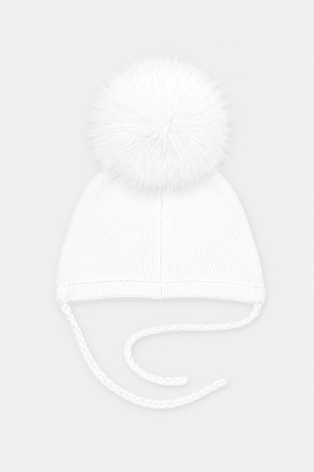 A white knit baby beanie hat featuring a large fluffy pom-pom on top and matching white ear tie strings, shown against a light gray background.