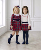 Two young girls wearing Miranda AW26 tartan collection dress and skirt and blouse set.  