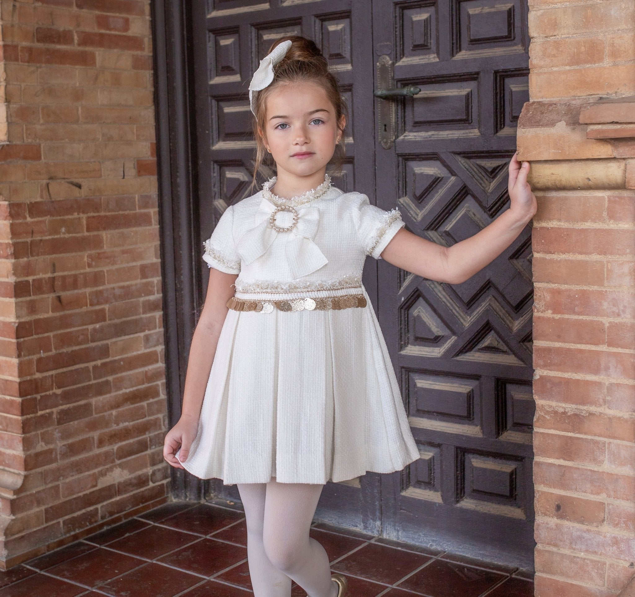 Naxos AW25 girls cream Chanel A-line dress with gold sequin waistband and pearl bow neckline