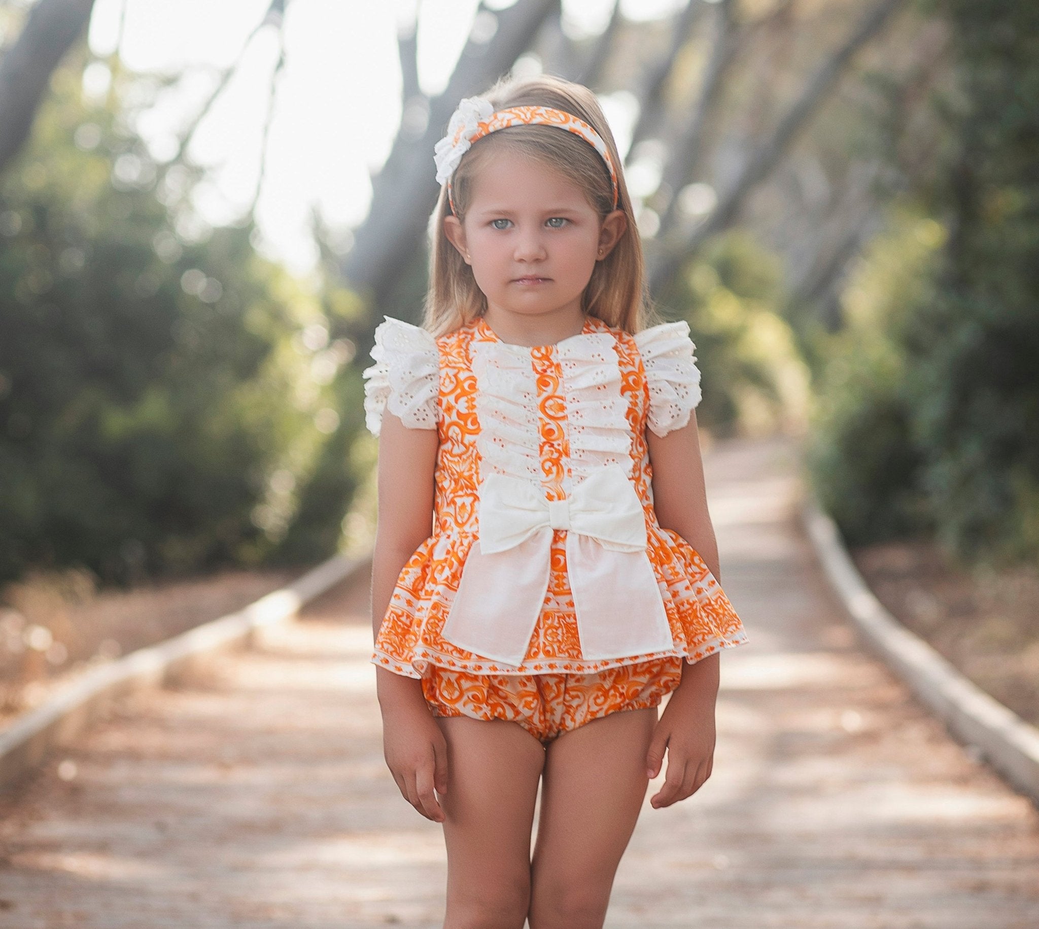 Little girl wearing Rochy SS26 Orange D&G Print Bloomer shorts Set. 