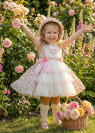 Young girl in a Sonata floral dress standing in a garden with flowers and a basket.