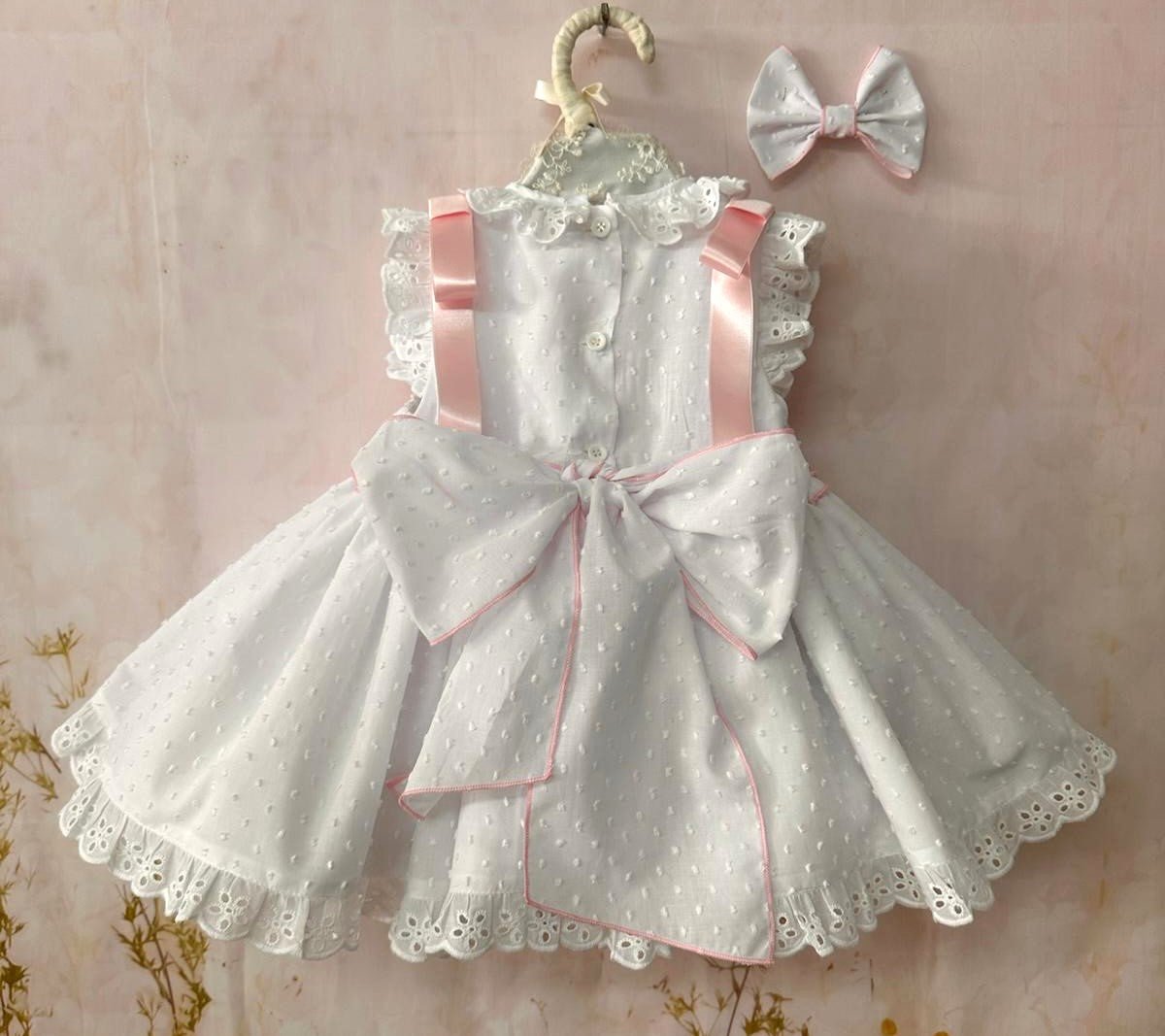 Girls white smocked Spanish dress with pink ribbon detail, broderie anglaise trims and full skirt back bow tie