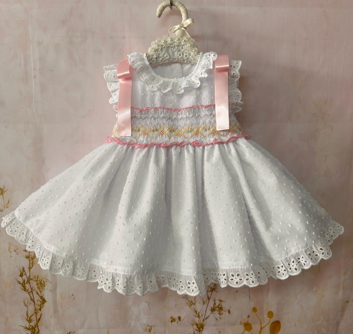 Child's white smocked Spanish dress with pink ribbon detail, broderie anglaise trims and full skirt