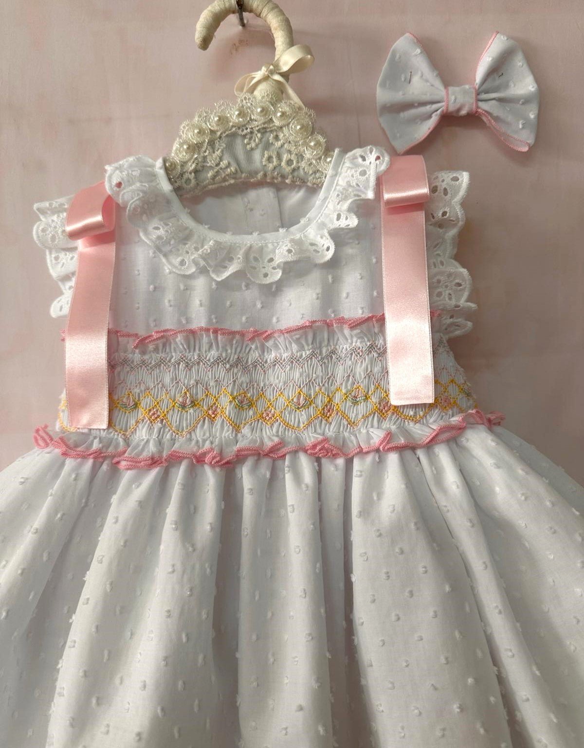 Girls white smocked Spanish dress with pink ribbon detail, broderie anglaise trims and full skirt